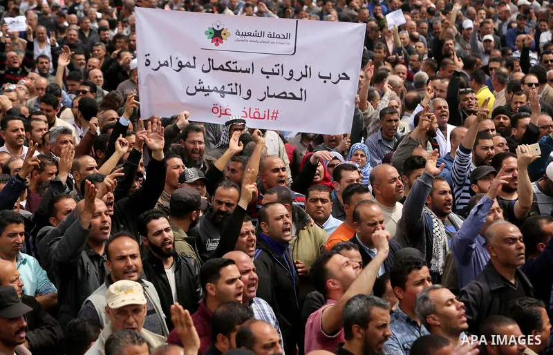 Palestinians, employed by the Palestinian Authority, chant slogans and wave placards during a demonstration against the decision to reduce their salaries in Gaza City on April 8, 2017. Photo by Ashraf Amra