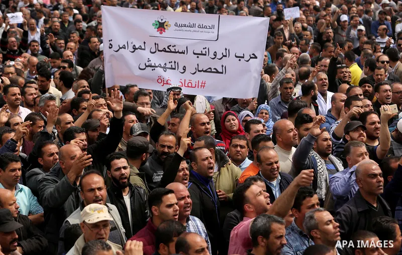 Palestinians, employed by the Palestinian Authority, chant slogans and wave placards during a demonstration against the decision to reduce their salaries in Gaza City on April 8, 2017. Photo by Ashraf Amra