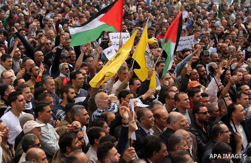 Palestinians, employed by the Palestinian Authority, chant slogans and wave placards during a demonstration against the decision to reduce their salaries in Gaza City on April 8, 2017. Photo by Ashraf Amra