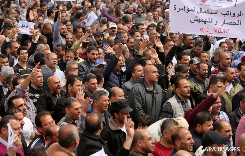Palestinians, employed by the Palestinian Authority, chant slogans and wave placards during a demonstration against the decision to reduce their salaries in Gaza City on April 8, 2017. Photo by Ashraf Amra