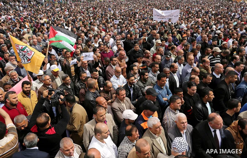 Palestinians, employed by the Palestinian Authority, chant slogans and wave placards during a demonstration against the decision to reduce their salaries in Gaza City on April 8, 2017. Photo by Ashraf Amra
