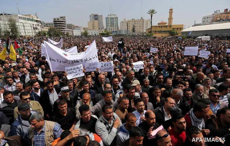 Palestinians, employed by the Palestinian Authority, chant slogans and wave placards during a demonstration against the decision to reduce their salaries in Gaza City on April 8, 2017. Photo by Ashraf Amra