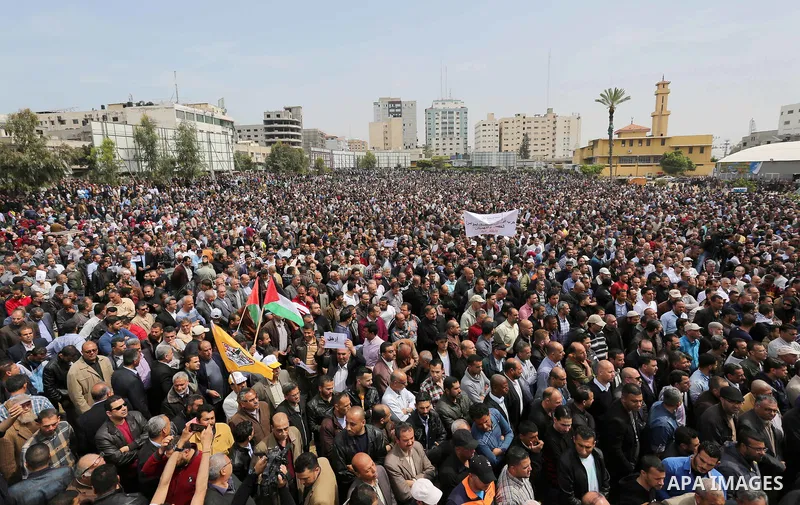 Palestinians, employed by the Palestinian Authority, chant slogans and wave placards during a demonstration against the decision to reduce their salaries in Gaza City on April 8, 2017. Photo by Ashraf Amra
