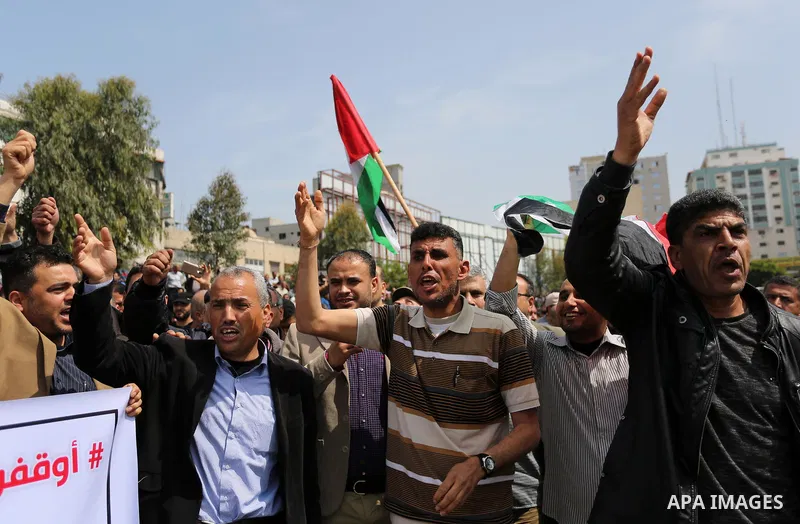 Palestinians, employed by the Palestinian Authority, chant slogans and wave placards during a demonstration against the decision to reduce their salaries in Gaza City on April 8, 2017. Photo by Ashraf Amra