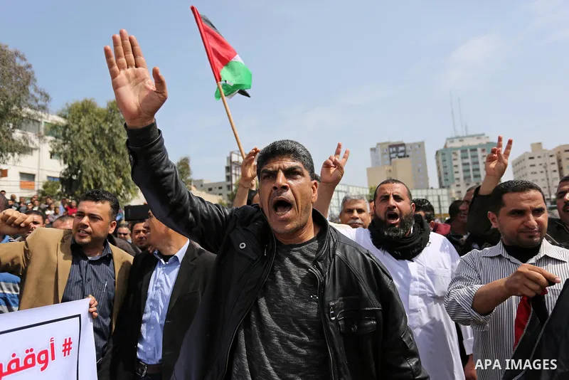 Palestinians, employed by the Palestinian Authority, chant slogans and wave placards during a demonstration against the decision to reduce their salaries in Gaza City on April 8, 2017. Photo by Ashraf Amra
