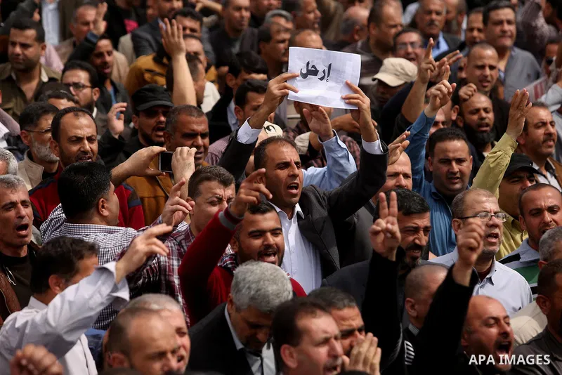 Palestinians, employed by the Palestinian Authority, chant slogans and wave placards during a demonstration against the decision to reduce their salaries in Gaza City on April 8, 2017. Photo by Ashraf Amra