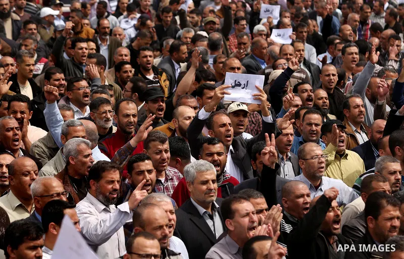 Palestinians, employed by the Palestinian Authority, chant slogans and wave placards during a demonstration against the decision to reduce their salaries in Gaza City on April 8, 2017. Photo by Ashraf Amra