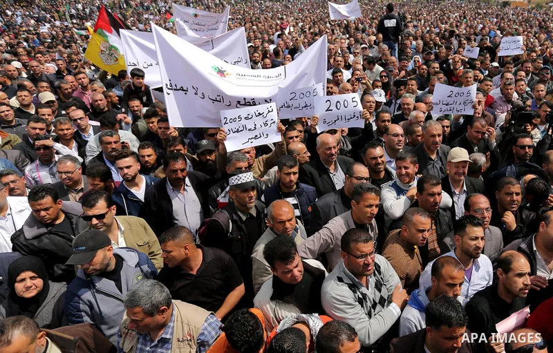 Palestinians, employed by the Palestinian Authority, chant slogans and wave placards during a demonstration against the decision to reduce their salaries in Gaza City on April 8, 2017. Photo by Ashraf Amra