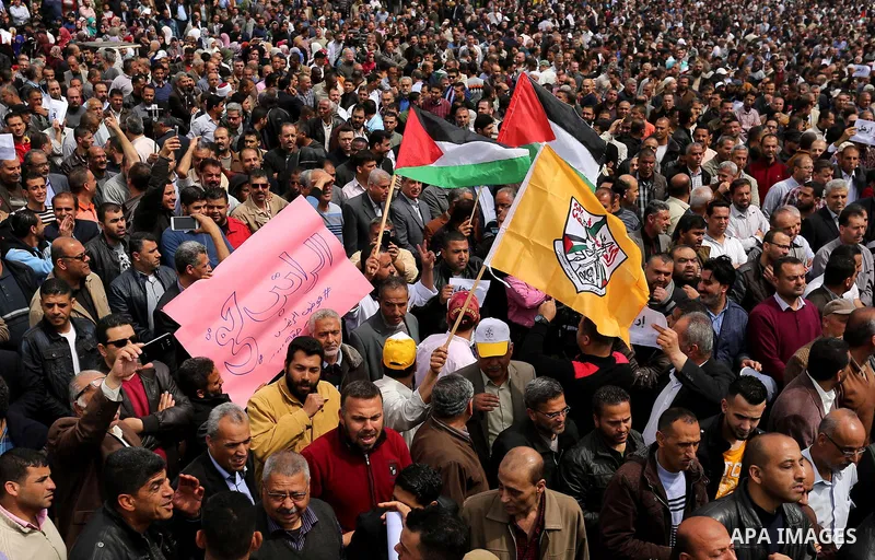 Palestinians, employed by the Palestinian Authority, chant slogans and wave placards during a demonstration against the decision to reduce their salaries in Gaza City on April 8, 2017. Photo by Ashraf Amra