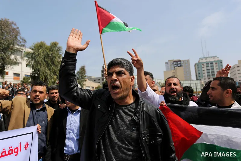 Palestinians, employed by the Palestinian Authority, chant slogans and wave placards during a demonstration against the decision to reduce their salaries in Gaza City on April 8, 2017. Photo by Ashraf Amra