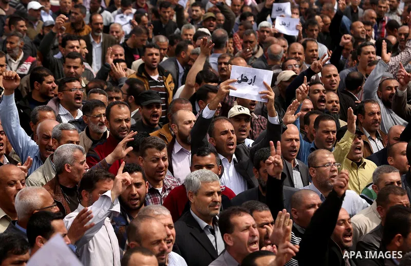 Palestinians, employed by the Palestinian Authority, chant slogans and wave placards during a demonstration against the decision to reduce their salaries in Gaza City on April 8, 2017. Photo by Ashraf Amra