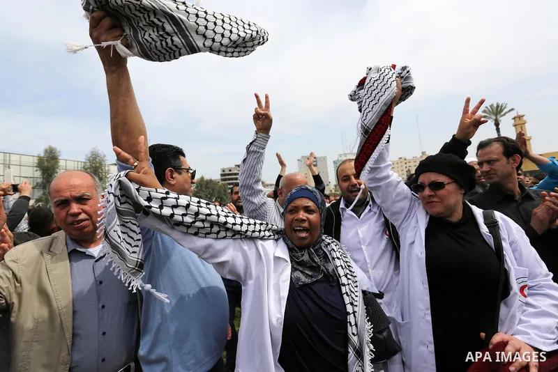 Palestinians, employed by the Palestinian Authority, chant slogans and wave placards during a demonstration against the decision to reduce their salaries in Gaza City on April 8, 2017. Photo by Ashraf Amra