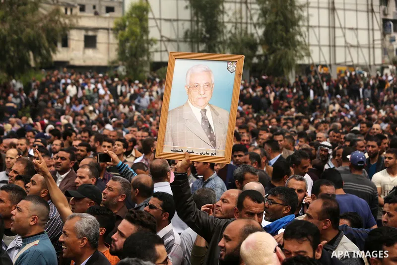 A Palestinian Authority employee holds a painted poster depicting President Mahmoud Abbas during a demonstration against the decision to reduce their salaries in Gaza City on April 8, 2017. Photo by Ashraf Amra