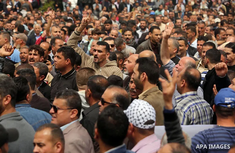 Palestinians, employed by the Palestinian Authority, chant slogans and wave placards during a demonstration against the decision to reduce their salaries in Gaza City on April 8, 2017. Photo by Ashraf Amra