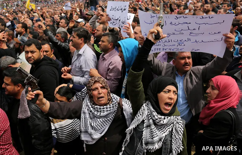 Palestinians, employed by the Palestinian Authority, chant slogans and wave placards during a demonstration against the decision to reduce their salaries in Gaza City on April 8, 2017. Photo by Ashraf Amra