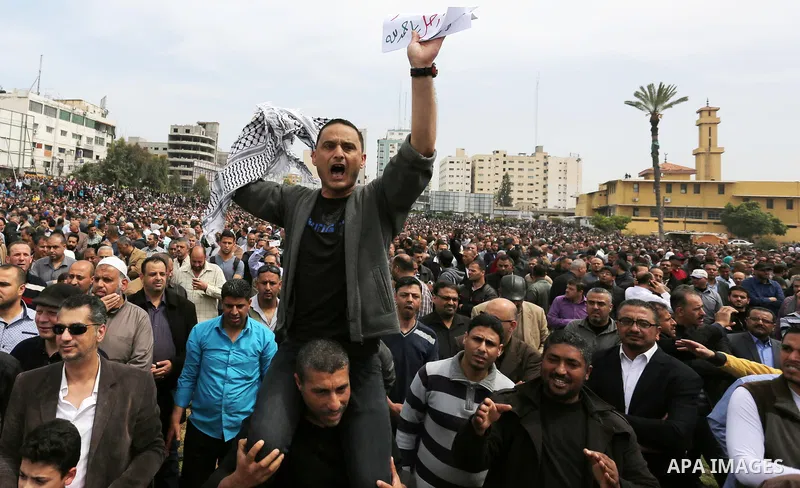 A Palestinian Authority employee holds a sign and chants slogans during a demonstration against the decision to reduce their salaries in Gaza City on April 8, 2017. Photo by Ashraf Amra