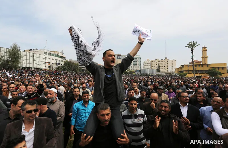 A Palestinian Authority employee holds a sign and chants slogans during a demonstration against the decision to reduce their salaries in Gaza City on April 8, 2017. Photo by Ashraf Amra