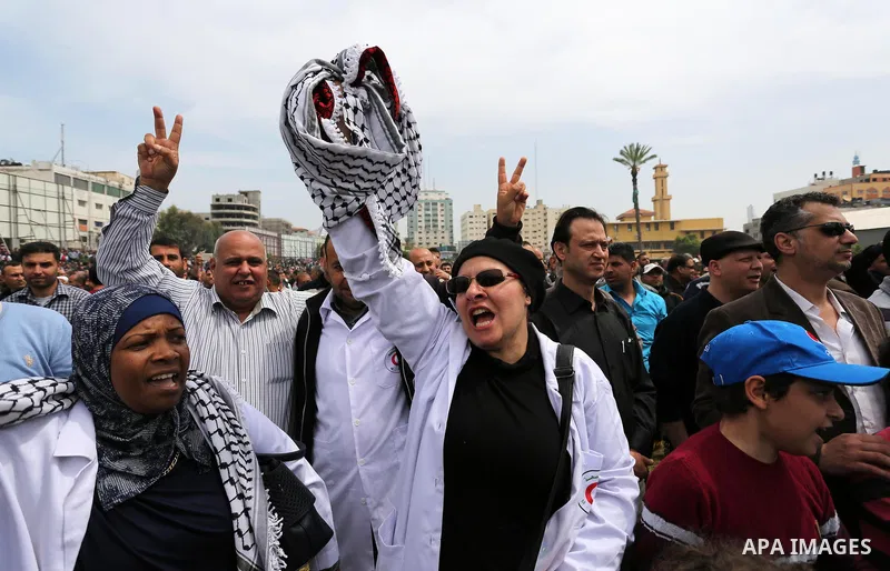 Palestinians, employed by the Palestinian Authority, chant slogans and wave placards during a demonstration against the decision to reduce their salaries in Gaza City on April 8, 2017. Photo by Ashraf Amra