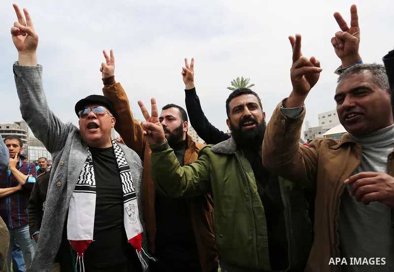 Palestinians, employed by the Palestinian Authority, chant slogans and wave placards during a demonstration against the decision to reduce their salaries in Gaza City on April 8, 2017. Photo by Ashraf Amra