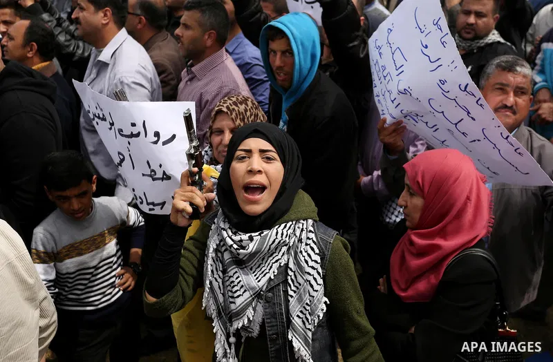 Palestinians, employed by the Palestinian Authority, chant slogans and wave placards during a demonstration against the decision to reduce their salaries in Gaza City on April 8, 2017. Photo by Ashraf Amra