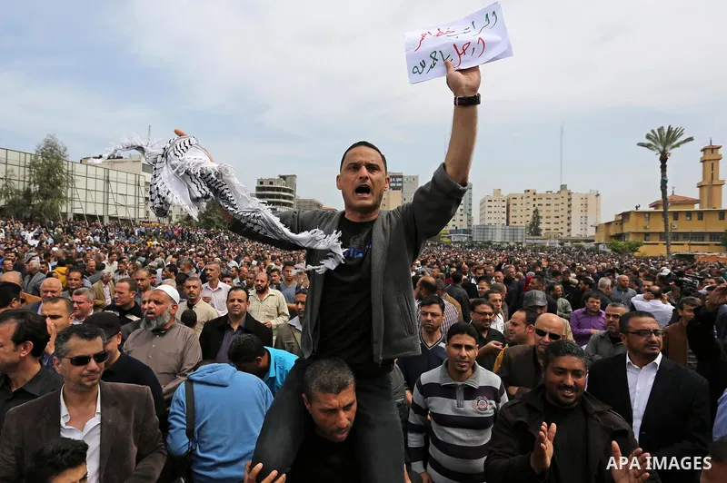 A Palestinian Authority employee holds a sign and chants slogans during a demonstration against the decision to reduce their salaries in Gaza City on April 8, 2017. Photo by Ashraf Amra