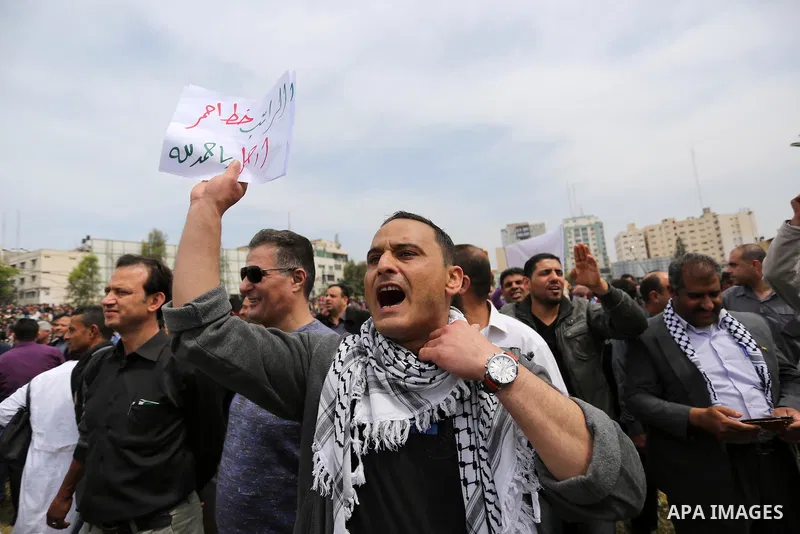 A Palestinian Authority employee holds a sign and chants slogans during a demonstration against the decision to reduce their salaries in Gaza City on April 8, 2017. Photo by Ashraf Amra