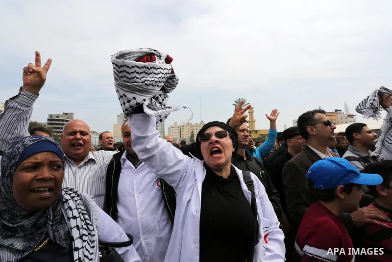 Palestinians, employed by the Palestinian Authority, chant slogans and wave placards during a demonstration against the decision to reduce their salaries in Gaza City on April 8, 2017. Photo by Ashraf Amra
