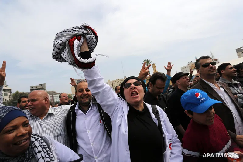 Palestinians, employed by the Palestinian Authority, chant slogans and wave placards during a demonstration against the decision to reduce their salaries in Gaza City on April 8, 2017. Photo by Ashraf Amra
