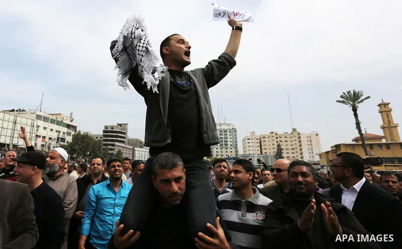 A Palestinian Authority employee holds a sign and chants slogans during a demonstration against the decision to reduce their salaries in Gaza City on April 8, 2017. Photo by Ashraf Amra