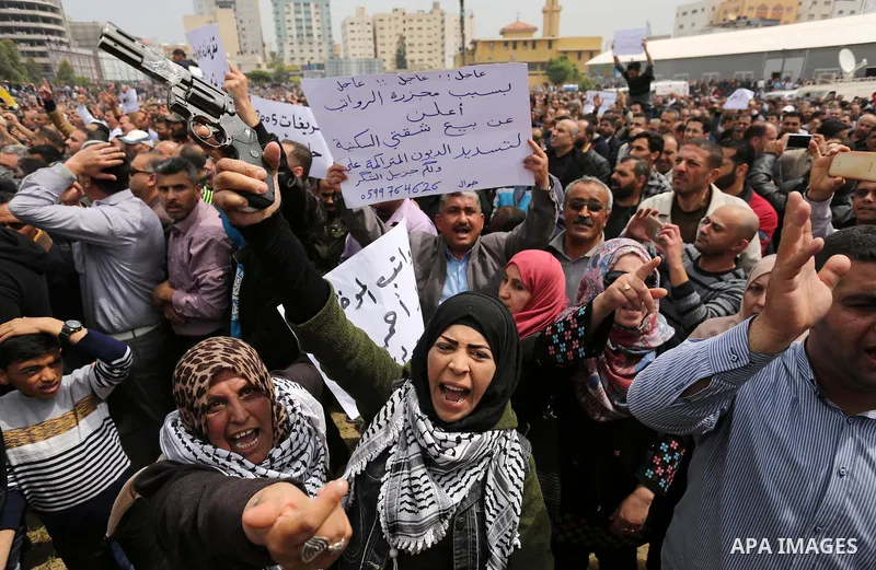 Palestinians, employed by the Palestinian Authority, chant slogans and wave placards during a demonstration against the decision to reduce their salaries in Gaza City on April 8, 2017. Photo by Ashraf Amra