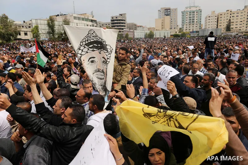 A Palestinian Authority employee holds a painted poster depicting late Palestinian leader Yasser Arafat during a demonstration against the decision to reduce their salaries in Gaza City on April 8, 2017. Photo by Ashraf...