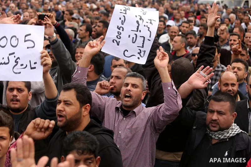 Palestinians, employed by the Palestinian Authority, chant slogans and wave placards during a demonstration against the decision to reduce their salaries in Gaza City on April 8, 2017. Photo by Ashraf Amra
