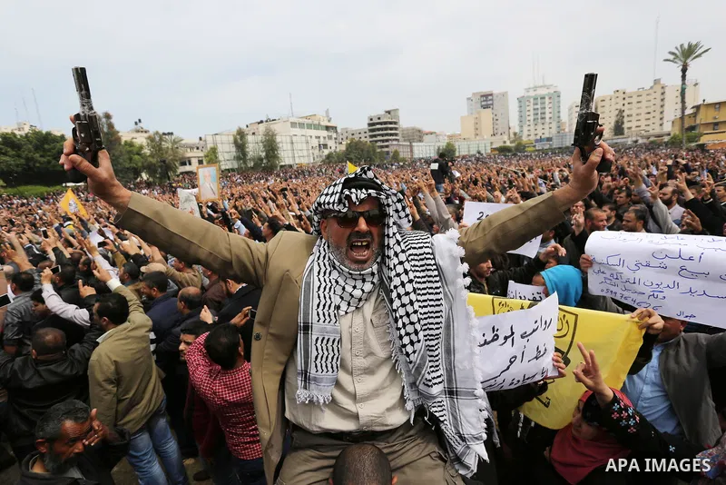 Palestinians, employed by the Palestinian Authority, chant slogans and wave placards during a demonstration against the decision to reduce their salaries in Gaza City on April 8, 2017. Photo by Ashraf Amra