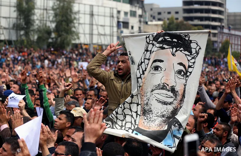 A Palestinian Authority employee holds a painted poster depicting late Palestinian leader Yasser Arafat during a demonstration against the decision to reduce their salaries in Gaza City on April 8, 2017. Photo by Ashraf...