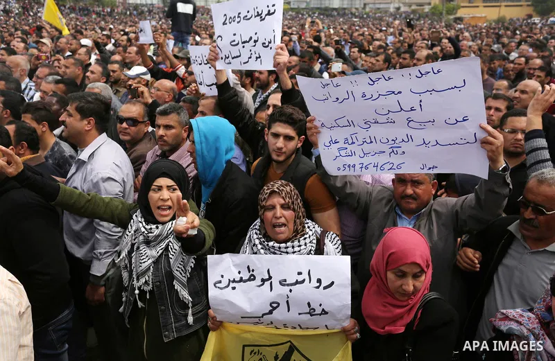 Palestinians, employed by the Palestinian Authority, chant slogans and wave placards during a demonstration against the decision to reduce their salaries in Gaza City on April 8, 2017. Photo by Ashraf Amra