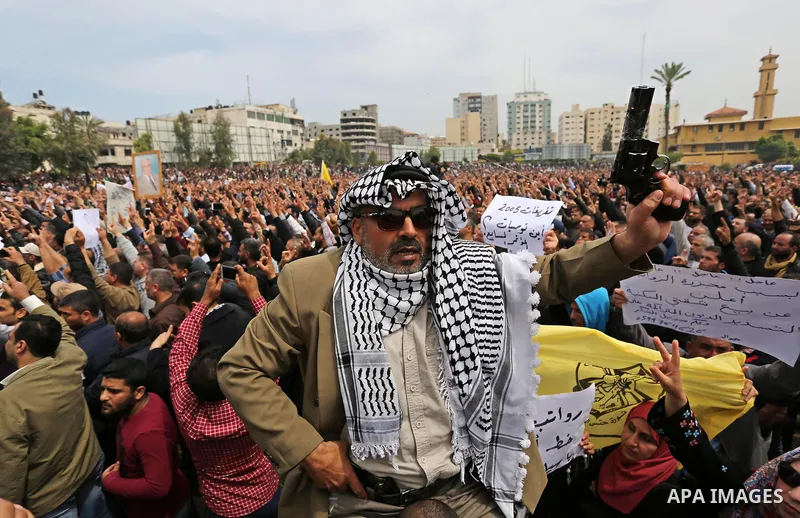 Palestinians, employed by the Palestinian Authority, chant slogans and wave placards during a demonstration against the decision to reduce their salaries in Gaza City on April 8, 2017. Photo by Ashraf Amra