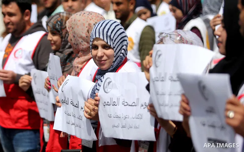 Palestinian doctors hold banners during a rally to mark the World Health Day, in Gaza city, on April 9, 2017. Photo by Ashraf Amra