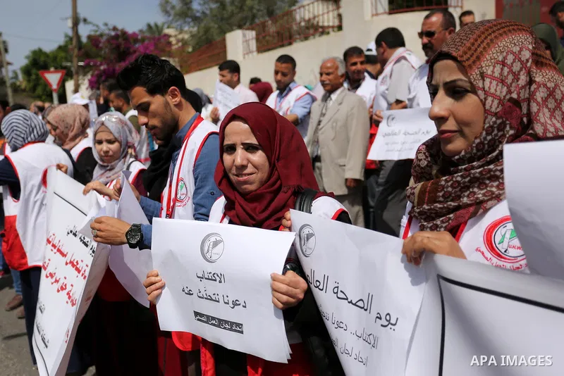 Palestinian doctors hold banners during a rally to mark the World Health Day, in Gaza city, on April 9, 2017. Photo by Ashraf Amra