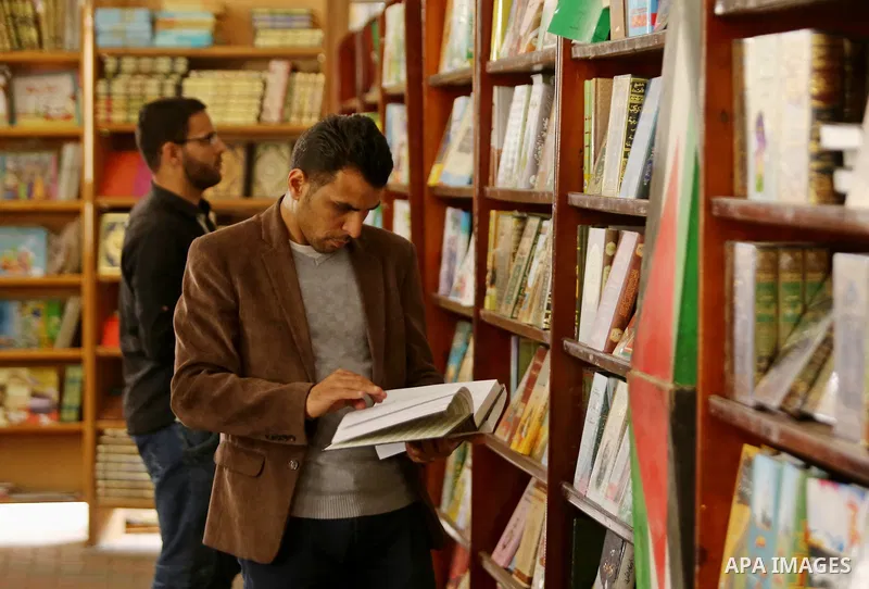 Palestinians browse through books on a stand at a book fair, in Gaza city on April 09, 2017. Photo by Ashraf Amra