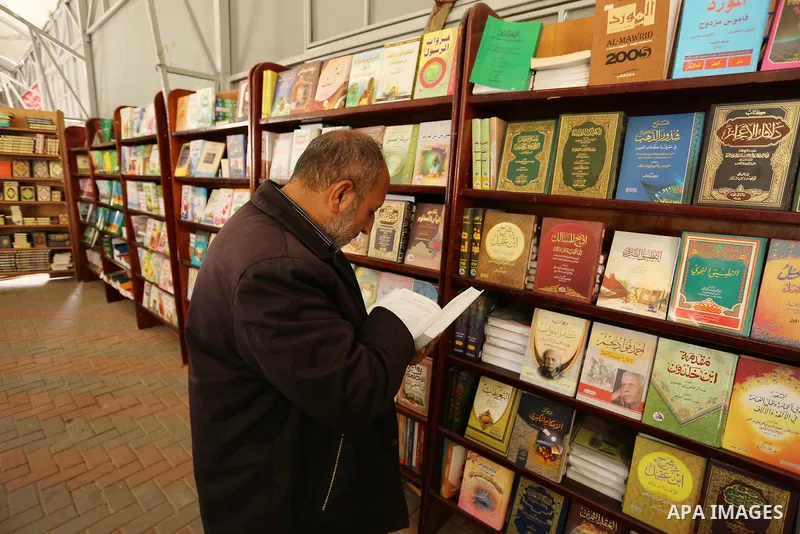 Palestinians browse through books on a stand at a book fair, in Gaza city on April 09, 2017. Photo by Ashraf Amra