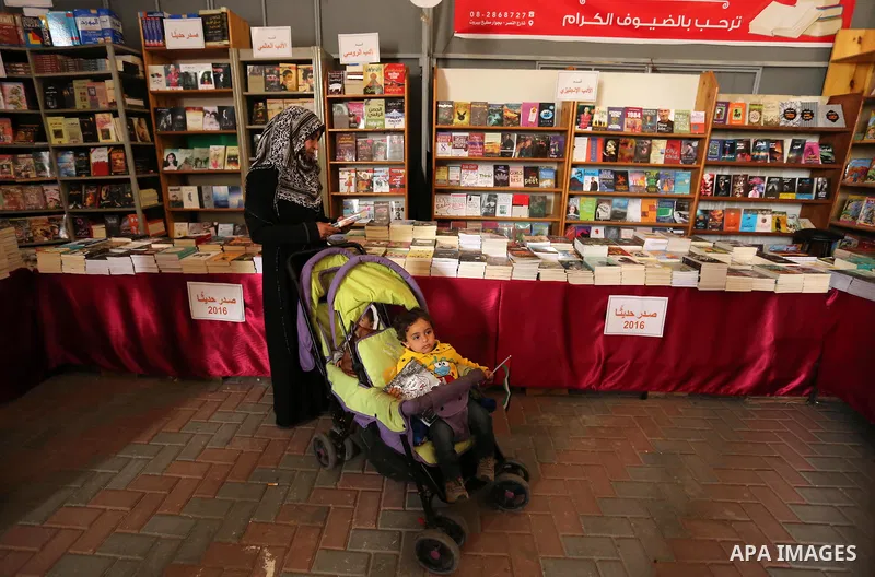 Palestinians browse through books on a stand at a book fair, in Gaza city on April 09, 2017. Photo by Ashraf Amra