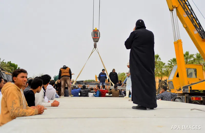 Egyptian workers use crane to lift coffins of the victims of the blast at the Coptic Christian Saint Mark's church in Alexandria the previous day during a funeral procession at the Monastery of Marmina in the city of Bor...