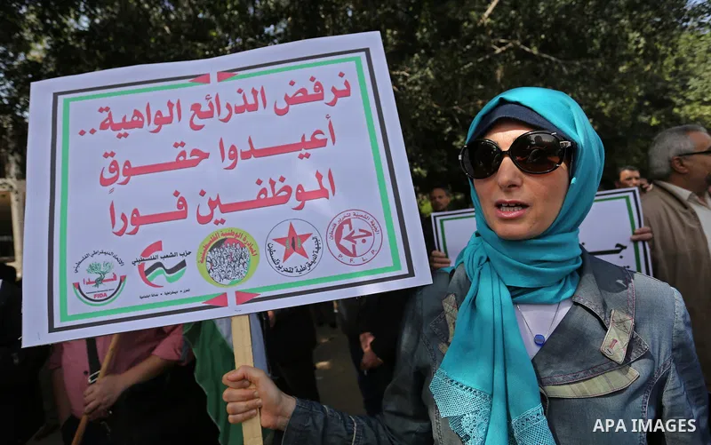 Palestinians employed by the Palestinian Authority, chant slogans and wave placards during a demonstration against the decision to reduce their salaries in Gaza City on April 11, 2017. Photo by Ashraf Amra