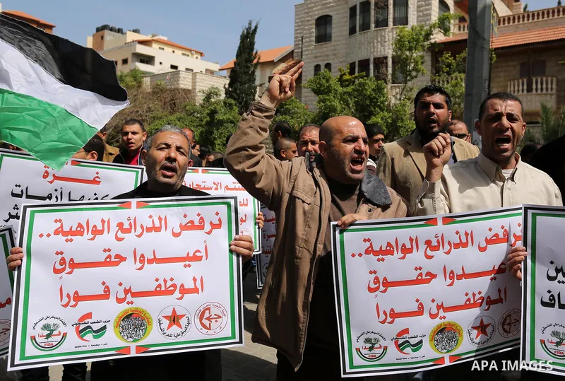 Palestinians employed by the Palestinian Authority, chant slogans and wave placards during a demonstration against the decision to reduce their salaries in Gaza City on April 11, 2017. Photo by Ashraf Amra
