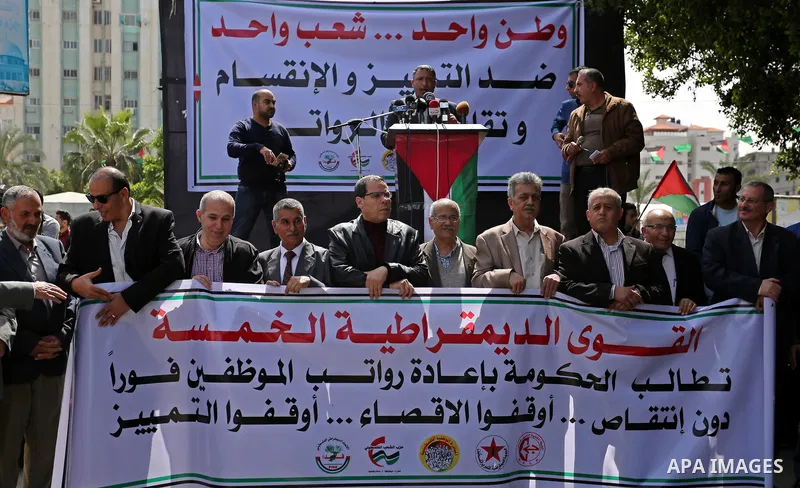 Palestinians employed by the Palestinian Authority, chant slogans and wave placards during a demonstration against the decision to reduce their salaries in Gaza City on April 11, 2017. Photo by Ashraf Amra