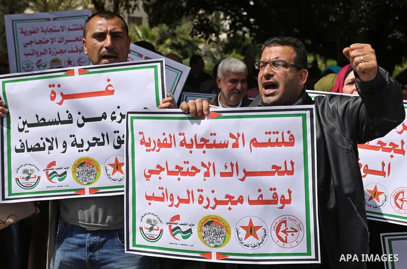 Palestinians employed by the Palestinian Authority, chant slogans and wave placards during a demonstration against the decision to reduce their salaries in Gaza City on April 11, 2017. Photo by Ashraf Amra