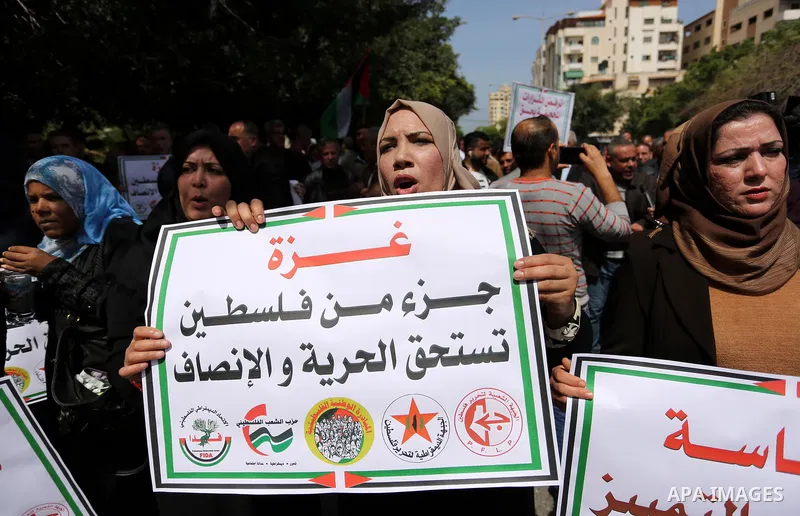 Palestinians employed by the Palestinian Authority, chant slogans and wave placards during a demonstration against the decision to reduce their salaries in Gaza City on April 11, 2017. Photo by Ashraf Amra