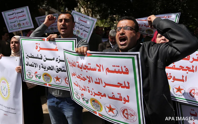 Palestinians employed by the Palestinian Authority, chant slogans and wave placards during a demonstration against the decision to reduce their salaries in Gaza City on April 11, 2017. Photo by Ashraf Amra