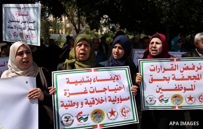 Palestinians employed by the Palestinian Authority, chant slogans and wave placards during a demonstration against the decision to reduce their salaries in Gaza City on April 11, 2017. Photo by Ashraf Amra