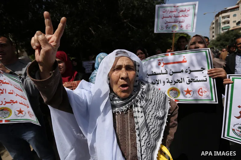 Palestinians employed by the Palestinian Authority, chant slogans and wave placards during a demonstration against the decision to reduce their salaries in Gaza City on April 11, 2017. Photo by Ashraf Amra